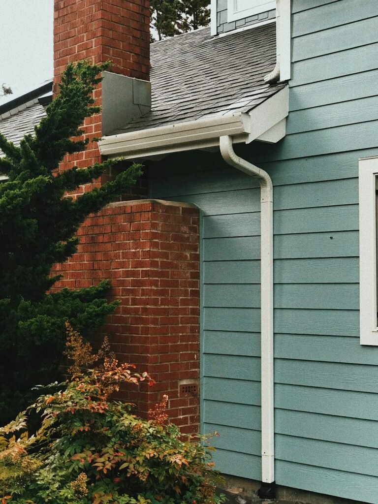 Blue-painted house with a red brick chimney and guttering along the roofline